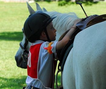 Youth member checking saddle before mounting horse