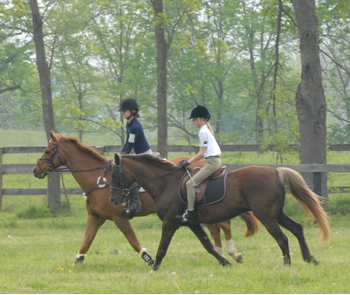 Two youth members riding their horses in the countryside