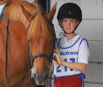 Youth member standing with her bridled horse